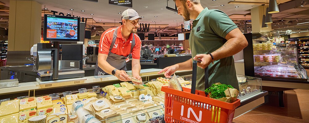 Ein Mann mit einem Einkaufskorb an der Käsetheke eines INTERSPAR-Hypermarktes