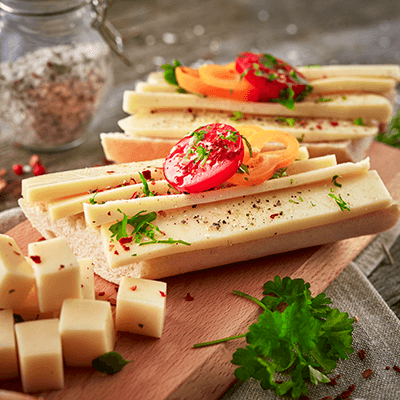 Ein aufgeschnittener Schnittkäse mit Tomaten und Kräutern auf einem Brot