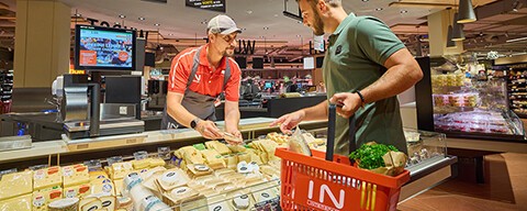 Ein Mann mit einem Einkaufskorb an der Käsetheke eines INTERSPAR-Hypermarktes