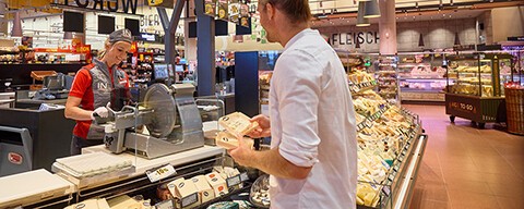 Ein Mann wird von einem INTERSPAR-Mitarbeiter an der Käsetheke beraten
