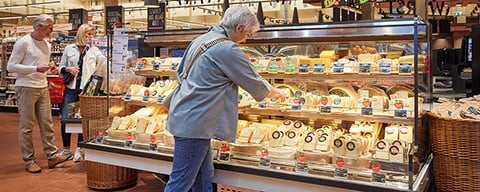 Eine Frau an einer INTERSPAR-Käsetheke beim Aussuchen von Käse
