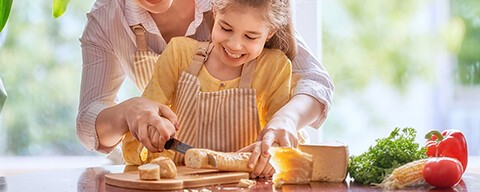 Eine Frau und ein kleines Mädchen schneiden gemeinsam Brot auf einem Brettchen