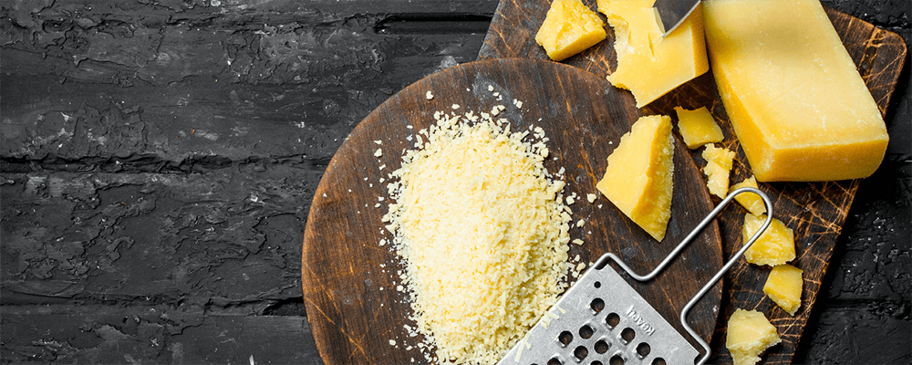 Verschiedene Käse und ein haußen mit geriebenem Käse auf einem Tisch