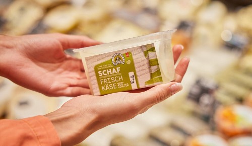 Eine  Person hält eine Verpackung Ziegen-Frischkäse in der Hand