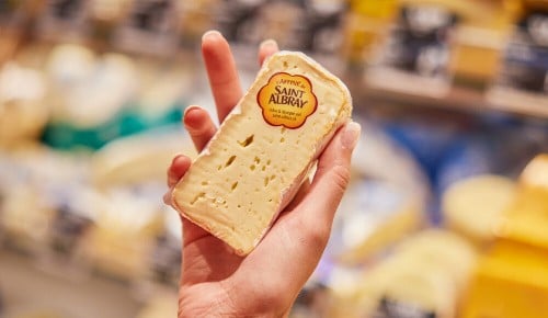 Eine Person hält ein Stück St. Albray-Weichkäse in der Hand