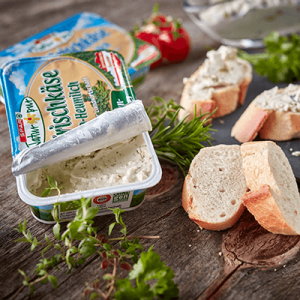 Eine Packung Kräuter-Frischkäse und ein aufgeschnittenes Baguette