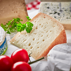 Ein Stück Weichkäse mit Tomaten und Petersilie auf einem Tisch