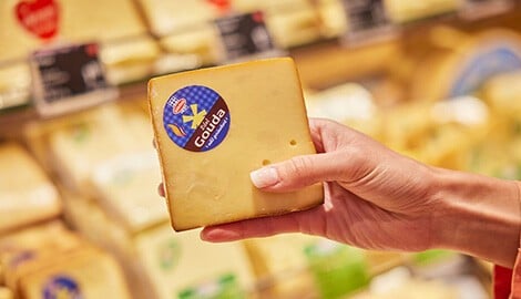 Eine Person hält ein Stück Schnittkäse in einem INTERSPAR in der Hand
