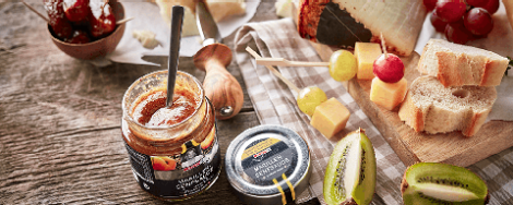 Ein Stück Hartkäse, Chutney und aufgeschnittene Kiwi auf einem Tisch