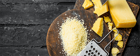 Verschiedene Käse und ein haußen mit geriebenem Käse auf einem Tisch