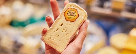 Eine Person hält ein Stück St. Albray-Weichkäse in der Hand