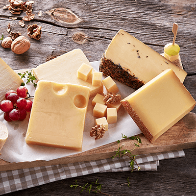 Verschiedene Stücke Hartkäse auf einem Holzbrettchen