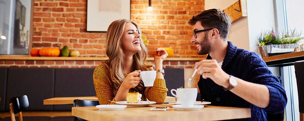 Ein junges Paar, das in einem Café Kaffee trinkt und Kuchen isst.