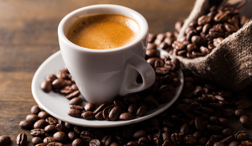 Eine Tasse Kaffee neben einem offenen Sack voller Kaffeebohnen