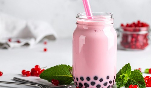 Ein pinker Bubble Tea mit dunklen Tapioka-Perlen in einem Joghurtglas