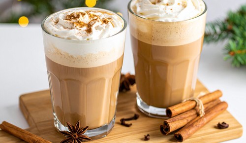 Zwei Gläser mit Chai Latte, garniert mit Schlagsahne und Zimt