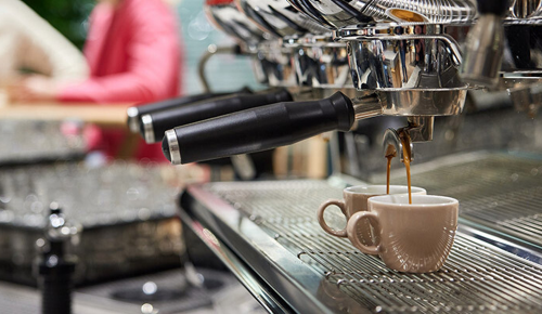 Frischer Kaffee läuft aus einer Kaffeemaschine in zwei Espressotassen