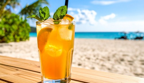 Ein Tea Spritz in einem große Glas auf einer Bank vor einem Strand