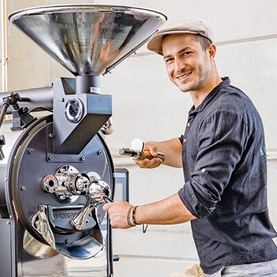 Ein Mitarbeiter von Kaffee Plantage an einer Kaffee-Röstmaschine