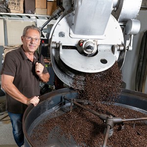 Ein Mitarbeiter von Kaffee Salcher neben einer Kaffeerösterei