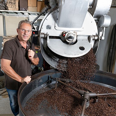 Ein Mitarbeiter von Kaffee Salcher neben einer Kaffeerösterei