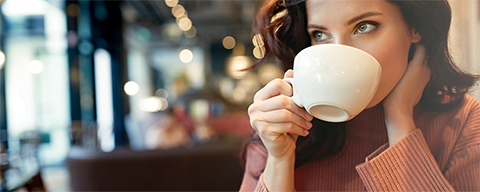 Eine Frau beim Trinken von Kaffee oder Tee aus einer weißen Tasse