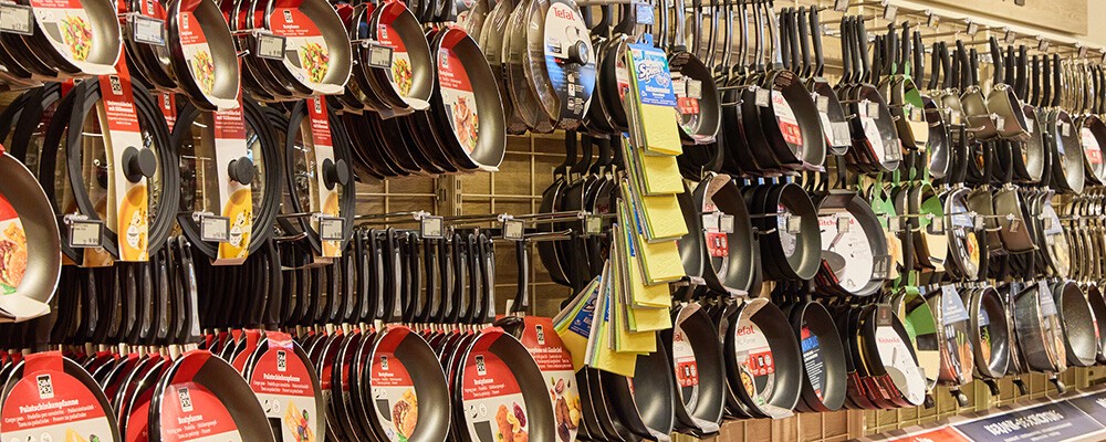 Mehrere Pfannen hängen an einem Regal in einem INTERSPAR-Hypermarkt