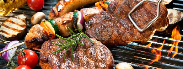 Fleisch, Gemüse, Mais und mehr liegen und grillen gerade auf einem Kugelgrill