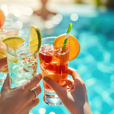 Mehrere Perspnen, die sich vor einem Pool mit Cocktail-Gläsern anprosten 