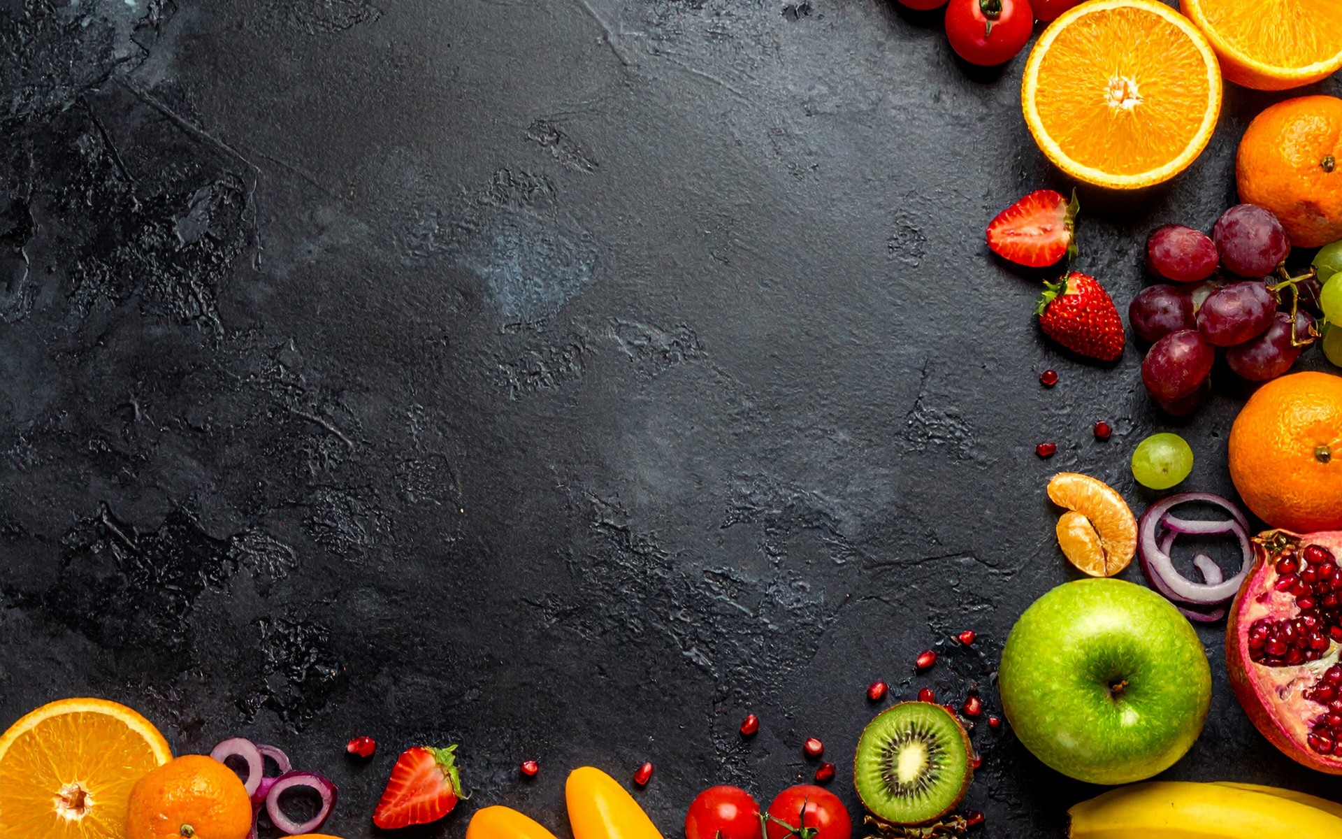 Verschiedene ganze und halbierte Obst- und Gemüsesorten auf einem dunklen Untergrund