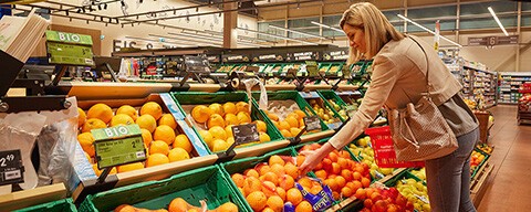 Eine Frau nimmt sich in einem INTERSPAR-Hypermarkt ein Sackerl Orangen