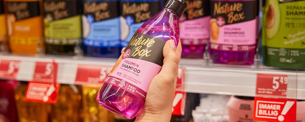 Eine Person hält eine pinke Shampoo-Packung in der Hand