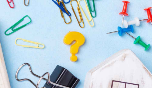 Eine schwarze Papierklammer, bunte Büroklammern und ein ?-Magnet