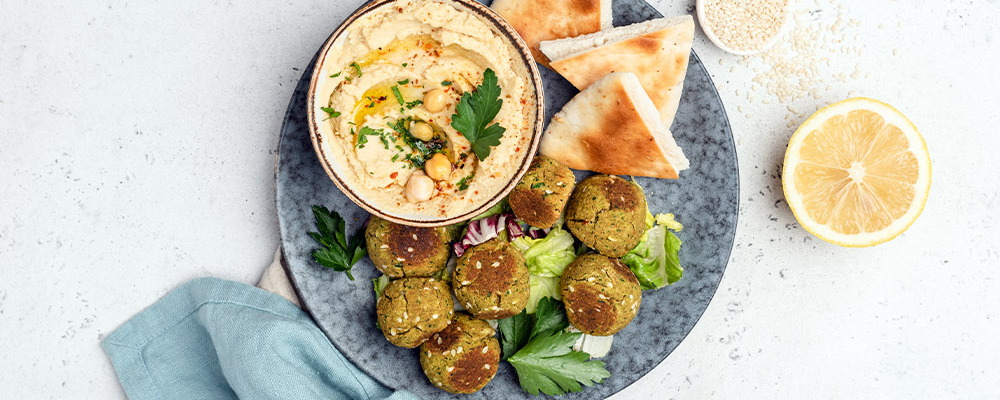 Eine Schale mit Humus und veganen Falafel auf einem Teller