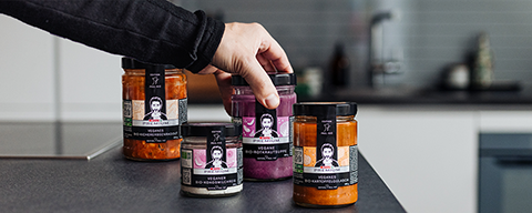 Eine Hand greift zu 4 SPAR Premium-Produkten auf einem Tisch