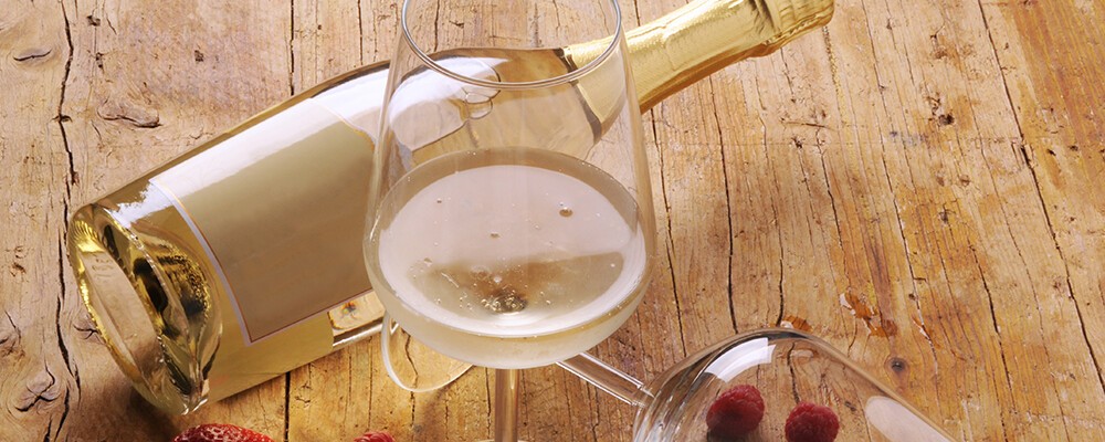 Eine Flasche Prosecco liegt neben einem Prosecco-Glas auf einem Tisch