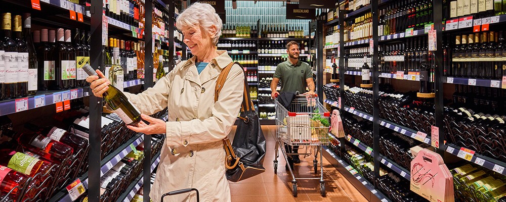 Eine Frau beim Einkaufen von einer Flasche Wein in einem INTERSPAR-Hypermarkt