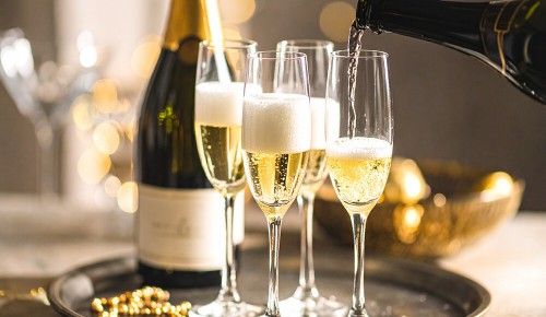 Vier gefüllte Champagnergläser neben einer Champagnerflasche