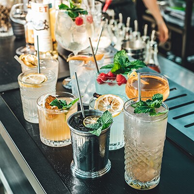 Mehrere Gläser mit verschiedenen Cocktails auf einem Bartresen
