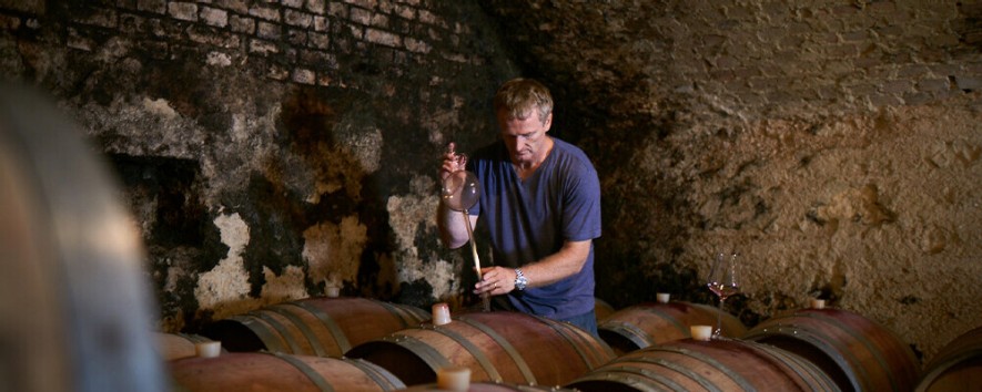 Paul Achs beim Pipettieren von Rotwein auf einem Weinfass