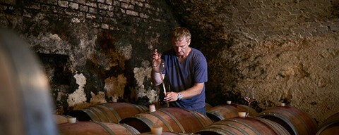 Paul Achs beim Pipettieren von Rotwein auf einem Weinfass