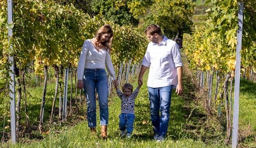 Winzer Markus Huber mit seiner Familie beim Spazieren durch Weinreben