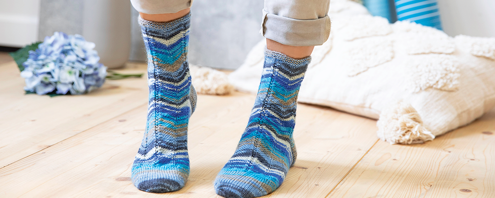 Eine Person steht mit blau-gemusterten Stricksocken in einem Raum