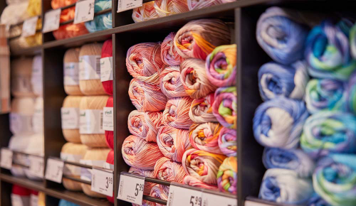 Viele verschieden farbigen Wollknäuel in einem INTERSPAR-Regal