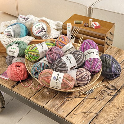 Verschiedene Wollknäuel und Strickzubehör in einem Körbchen