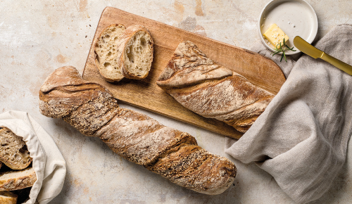 Ein rustikales angeschnittenes Brot auf einem Holzbrett 
