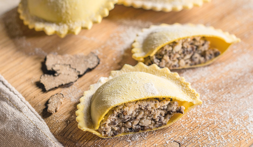 Frische Ravioli gefüllt mit Trüffeln und Steinpilzen auf einem Holzbrett