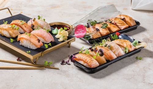 Verschiedene Sushi in To-Go-Verpackungen und auf einer Platte