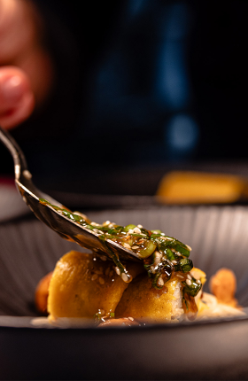 Knödel werden mit Sauce und einem feinen Topping garniert