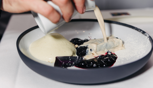 Ein Dessert mit Vanillesauce in einem Teller angerichtet